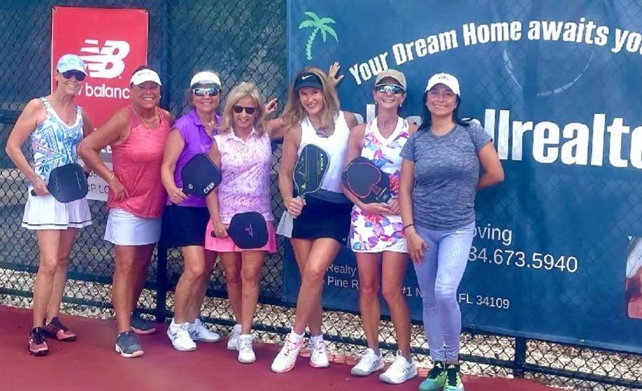 Players in front of Jill Jacobs' "Your dream home awaits you" pickleball banner