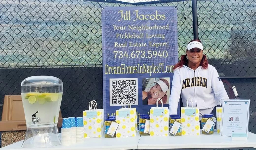 Jill Jacobs at her "Your Neighborhood Pickleball Loving Real Estate Expert" booth beside the pickleball courts
