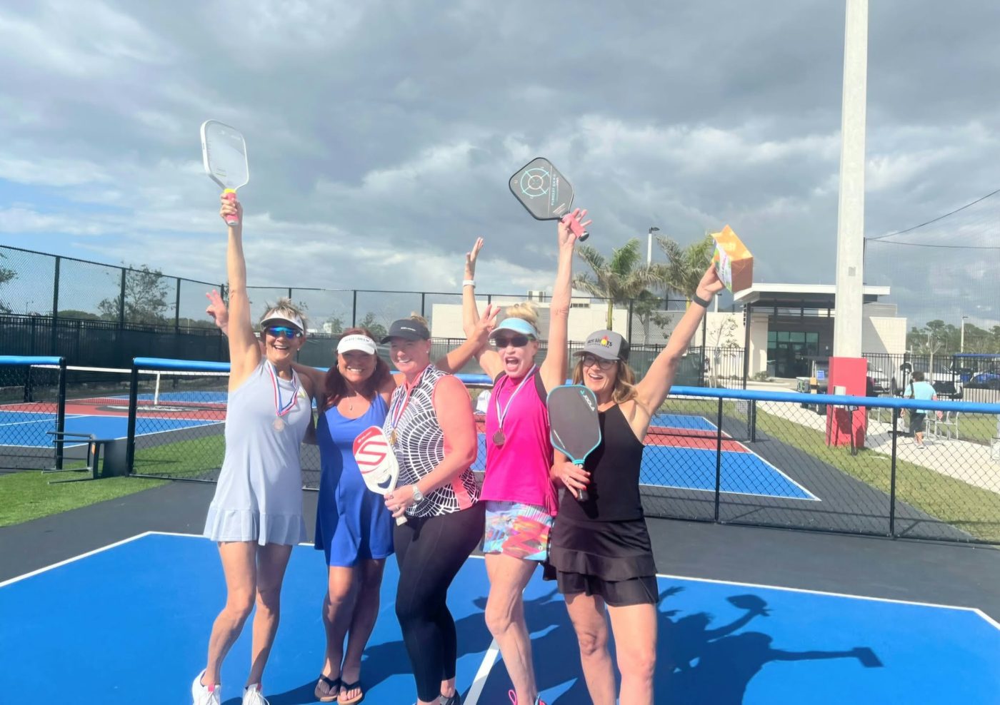 Pickleball players celebrating with medals and raised paddles