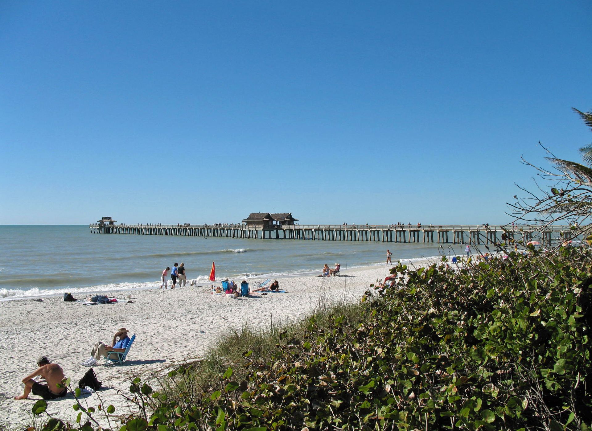 Naples Pier and white-sand beach on a sunny day in Naples, Florida